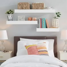 a bed with white sheets and pillows in a bedroom next to two bookshelves