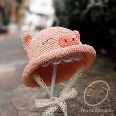 a crocheted pink hat with a white ribbon around the brim and eyes