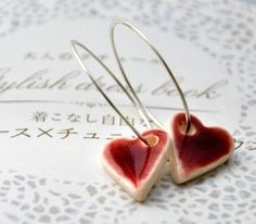 two heart shaped earrings sitting on top of a piece of paper