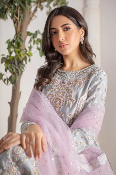 Refreshing Ice blue hued, relaxed silhouette shirt crafted from Pure silk net, fully hand block printed and embellished with tila , dabka, opaque sequins, beads, pearls over a myriad of colorful floral embroidery stylized beautifully. Stunning lilac net dupatta with heavily sprinkled sequins, finished with block printed borders and gota borders adds a fun festive element. This stunning kurta is paired with jamawar izaar pants to complete the look of this outfit, perfect for all celebratory festivities. Shirt Fabric: Pure Silk Net Shirt Length: 48” (customisable, mention in order notes) Pant Fabric: Jamawar Dupatta Fabric: Net Shirt & Pant Color: Ice Blue Dupatta Color: Lilac snow This outfit is fully lined Please refer Size Guide Before selecting size For Customised measurements please sel Light Blue Long Sleeve Salwar Kameez With Dabka Work, Festive Light Blue Dupatta With Intricate Embroidery, Embroidered Light Blue Dupatta For Eid, Blue Sequined Dupatta, Light Blue Dabka Embellished Long Sleeve Kurta, Net Dupatta, Pakistani Designers, Ice Blue, Blue Hues