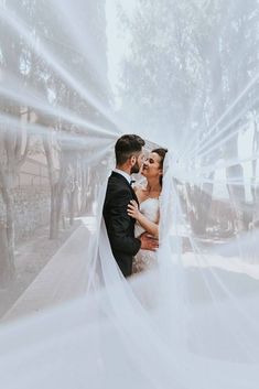 a bride and groom are posing under veils