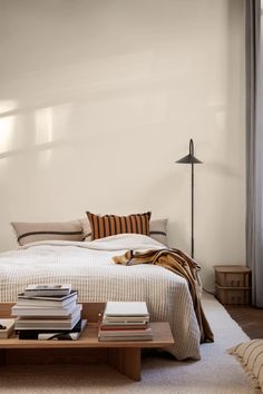 a bed sitting next to a table with books on top of it in a bedroom