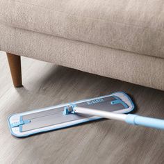 a mop laying on the floor next to a couch with it's handle extended