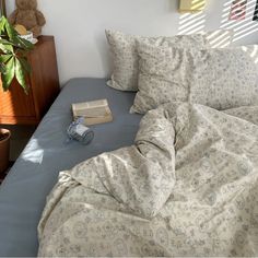 an unmade bed with two pillows and a book on the pillowcase next to it