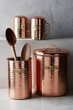 three copper colored pots with spoons and lids