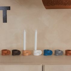 candles are lined up on a table with different shapes and sizes in front of them