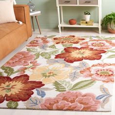 a living room area with a couch, table and flower rug on the floor in front of it