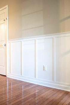 an empty room with hard wood floors and white paneling on the walls is shown