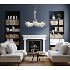 a living room filled with furniture and a fire place under a chandelier in front of a fireplace