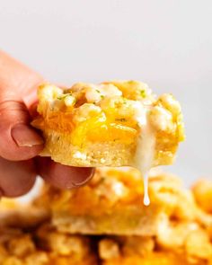 a hand holding up a piece of cornbread casserole with melted cheese on top