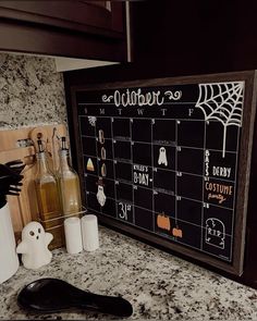 a kitchen counter top with a calendar on it and halloween decorations next to it,