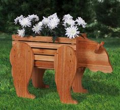 a wooden bear planter with white flowers in it