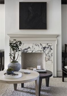 a living room with two tables and a painting on the wall above it's fireplace