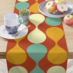 a table topped with plates and cups filled with fruit next to an apple on top of a wooden table