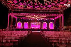 an outdoor event venue with rows of chairs and lights on the ceiling, all lit up at night