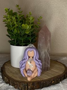 a small figurine sitting on top of a wooden table next to a potted plant