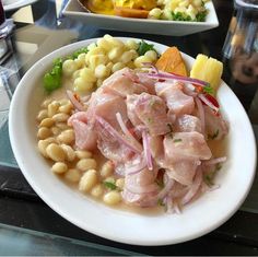 a white plate topped with meat and veggies on top of a glass table