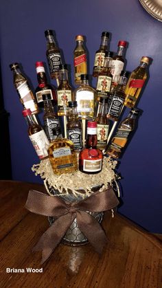 a basket filled with liquor bottles on top of a wooden table next to a blue wall