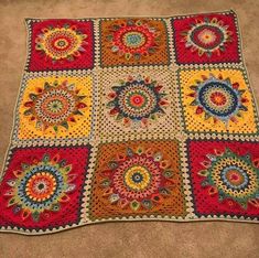 a crocheted blanket is laying on the floor in front of a carpeted floor