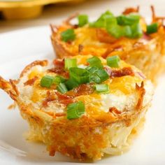 two mini quiche cups on a white plate with green onions and bacon in the middle