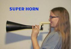 a woman with glasses is looking into a black and white horn that reads, super horn