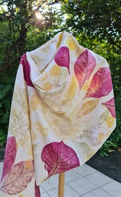 a white scarf with pink and yellow leaves on it