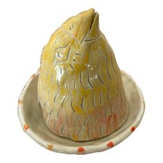 a yellow and white ceramic animal sitting on top of a saucer in the shape of a pear