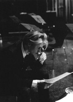 a black and white photo of a woman sitting at a table with music sheets in front of her