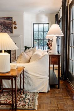 a living room filled with furniture and two lamps on either side of the couches