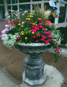 a planter filled with lots of flowers sitting on top of a sidewalk