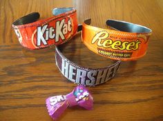 three candy wrap bracelets sitting on top of a wooden table next to a chocolate bar