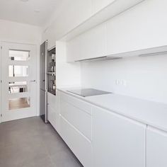 an empty kitchen with white cabinets and stainless steel appliances