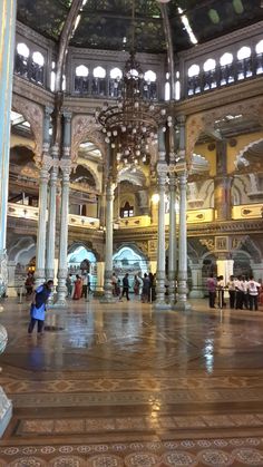 the inside of a large building with many people standing around and looking at something on the ground