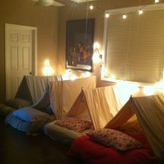 a room with several beds and lights on the ceiling, in front of a window