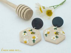 two earrings with flowers on them next to a beehive and a honey comb