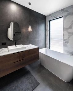 a bathroom with a large white tub next to a sink under a round mirror on the wall