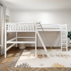 a white bunk bed sitting on top of a hard wood floor next to a potted plant