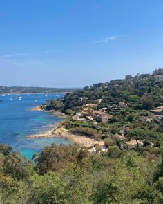 an aerial view of the ocean with boats in the water and trees on the shore