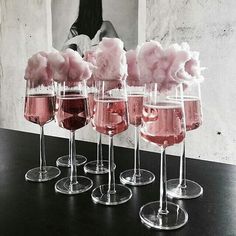 five wine glasses filled with pink liquid and cotton floss in front of a photo