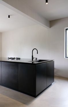 an empty kitchen with a black sink and counter top next to a window in the room