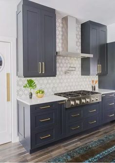 a kitchen with dark blue cabinets and white counter tops, gold trim on the backsplash