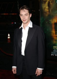 a young man in a tuxedo standing on a red carpet at an event