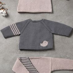 three knitted sweaters and two hats are laid out on the floor