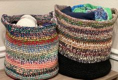 two crocheted baskets sitting on top of a wooden shelf next to each other