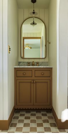 a bathroom with a checkered floor and large mirror above the sink, in front of an arched doorway