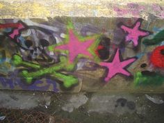 graffiti on the side of a concrete wall with stars and flowers painted on it in different colors