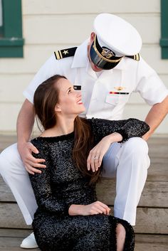 a woman sitting on the ground next to a man in a sailor's uniform