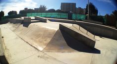 a skateboard park with ramps and railings in the foreground is seen through a fish - eye lens