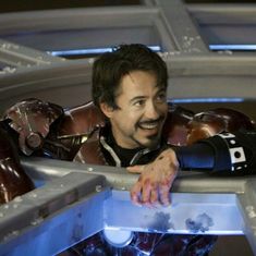 the iron man is smiling while standing on top of a giant metal structure with his arms outstretched