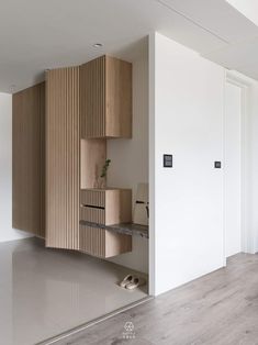 an empty room with wooden shelves and shoes on the floor next to each other in front of a white wall